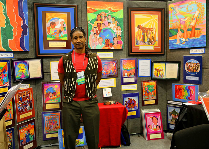 photo of an artist at an exhibit booth with paintings